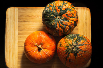 three pumpkins on a wooden board