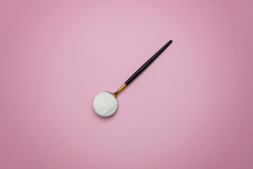 collagen protein powder on a modern spoon on pink background