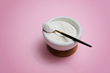 collagen protein powder in a bowl with a modern spoon on pink background