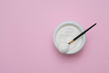 collagen protein powder in a bowl with a modern spoon on pink background