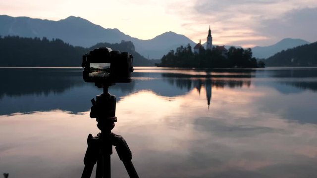 A beautiful reflection of Lake Bled at sunrise. Beautiful morning at lake bled with the castle and alps in the background. Camera taking photos of the island in Lake Bled and the church at sunrise