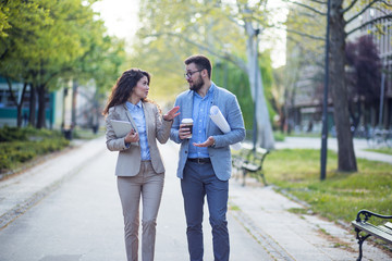 Businesswoman and businessman walking in a park and discussing