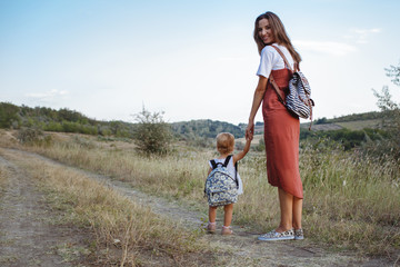 Happy mother and daughter on a field with backpacks.