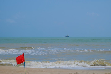 The sea has high waves, clear skies and a cargo ship.