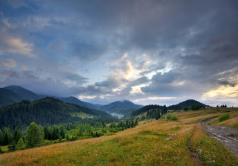 Amazing mountain landscape with fog and with a dirt road. Autumn evening in the Carpathians