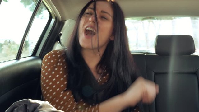 Happy beautiful woman dancing in car listening music