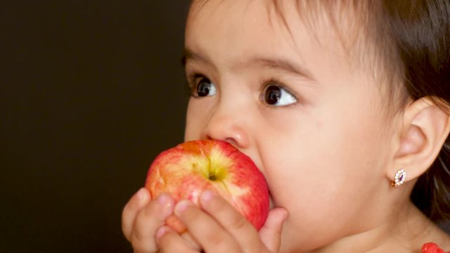 girl child in a red t-shirt eating a red apple