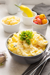 Baked macaroni and cheese, inside a bowl, on top of white kitchen table.