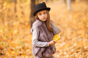 Emotional portrait of a tired and lonely little girl. Autumn mood. Walk in the autumn park. Lifestyle.