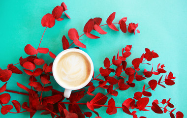 Cup of cappuccino with red eucalyptus neo mint color background .