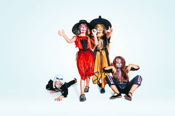 Kids or teens like witches and vampires with bones and glitter on white background. Caucasian models looks scary and playful. Halloween, black friday, sales, autumn holidays concept. The night of fear