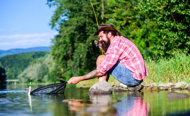 Man at riverside enjoy peaceful idyllic landscape while fishing. Man catching fish. Guy fly fishing. Successful fly fishing. Hobby for soul. United with nature. Fisherman fishing technique use rod