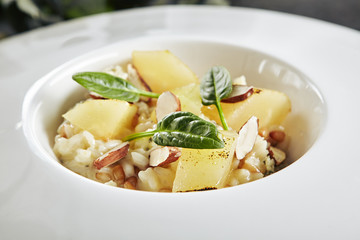 Exquisite Serving White Restaurant Plate of Risotto with Gorgonzola Cheese, Raisins, Almonds and Baked Pear Top View