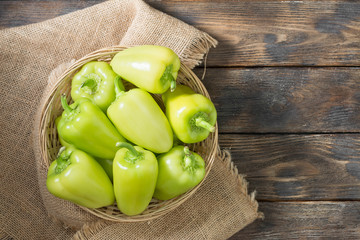 Green bell peppers in a basket on a wooden table. rustic style. Top view