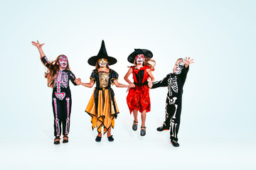 Kids or teens like witches and vampires with bones and glitter on white background. Caucasian models looks scary and playful. Halloween, black friday, sales, autumn holidays concept. The night of fear
