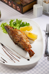 Roasted river fish on white plate