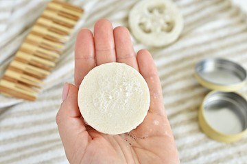 Woman holding solid shampoo bar with foam, zero waste bathroom, natural, plastic free product