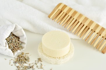 Solid shampoo bar with lavender, wooden hair comb and white towel on background, zero waste bathroom