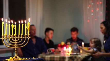 Jewish family Celebrates Hanukkah by lighting menorahs at sunset