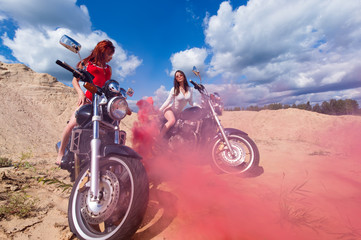 Obraz na płótnie Canvas two sensual woman on motorbikes with red smoke
