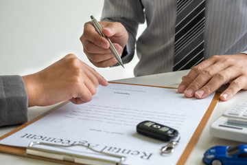 Car dealership provides advice about insurance details and car rental information and delivers the keys after signing the rental contract