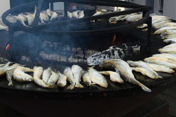 Herring being cooked outdoors on a brazier