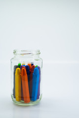 Colourful school supplies, colourful stationery markers in a transparent jar  on white background - space for caption