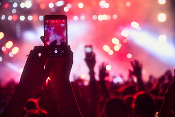 People taking photographs with touch smart phone during a music entertainment public concert