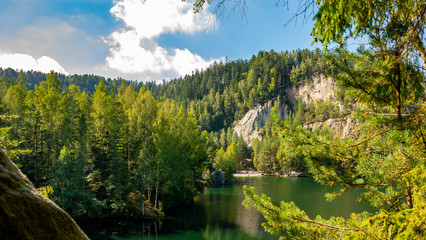 Fototapeta na wymiar Lake and ancient pines growing between them located in rock city Adrspach, National park of Adrspach, Czech Republic 