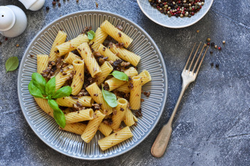 Rigatonni pasta with sauce and fried bacon on the kitchen table.