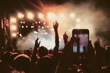 People taking photographs with touch smart phone during a music entertainment public concert
