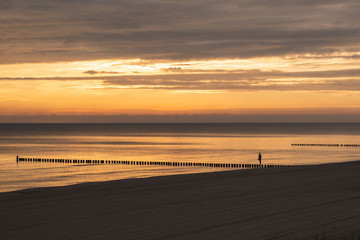 Ein Mensch steht an einem Strand bei Sonnenuntergang 
