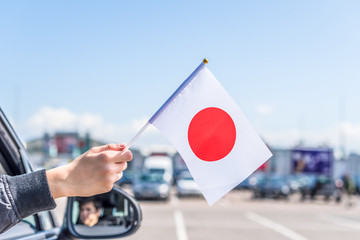 Boy holding Japan, Flag from the open car window on the parking of the shopping mall. Concept