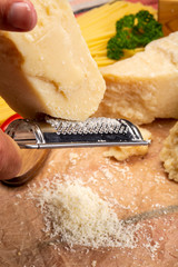 Man cooking with hard italian cheese, grated parmesan or grana padano cheese, hand with grater
