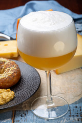 Cold belgian beer in glass served in cafe with variety of hard cheeses, tasty european food