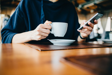 Woman in a cafe holds a mobile phone