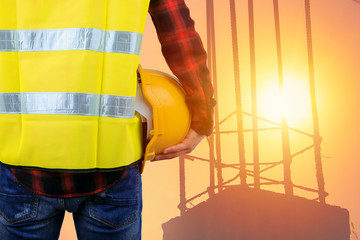 Engineer holding yellow helmet,Construction worker with helmet and steel structure background,Sunset construction site