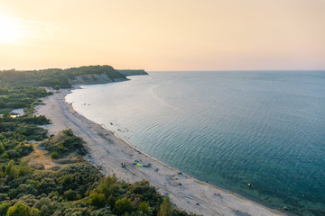 landscape top view of the sea coast with a sandy beach and a cliff in the distance during sunset