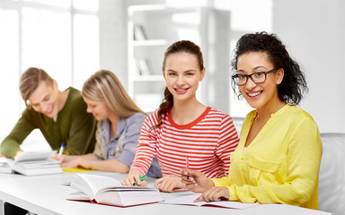 Fototapeta premium education, learning and people concept - happy high school student girls or classmates with books and notebooks