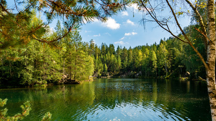 Fototapeta na wymiar Lake and ancient pines growing between them located in rock city Adrspach, National park of Adrspach, Czech Republic 