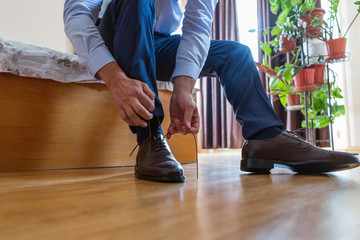 the groom puts on his wedding shoes. a man in a suit puts on his shoes. preparation for the event.