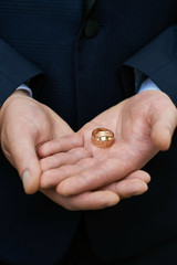 Groom holds wedding rings in his hands.