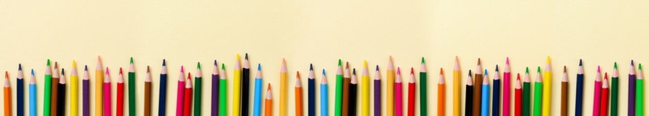Multicolored wooden pencils for school on yellow paper background. School and office stationery on yellow background. Concept back to school. Banner with copy space.