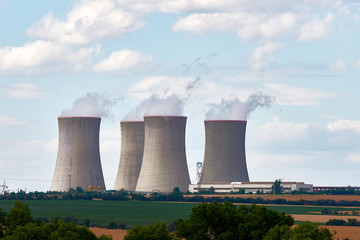 View of cooling chimneys of nuclear power plant. Landscape with forest and trees, green lawn under...