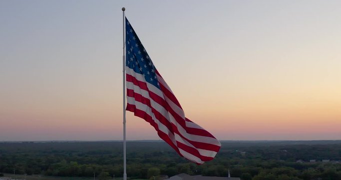 Slow orbit around an American Flag Waving in the wind against A Sunset Sky | Cinematic 4K aerial Video