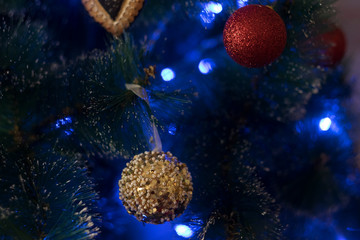 beautiful close up of christmas tree with blue ligts and golden balls attatched