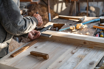 Close up photo of old hands of master carpenter that holding ruler and pencil, makes measurements