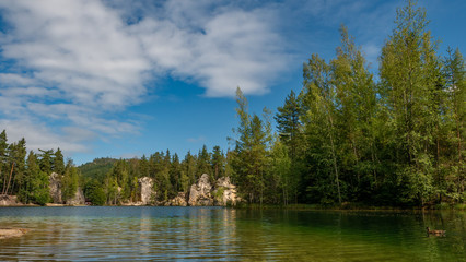 Lake and ancient pines growing between them located in rock city Adrspach, National park of Adrspach, Czech Republic 