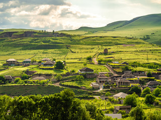 Fototapeta na wymiar Green hillside in Georgia with a small village at its foot
