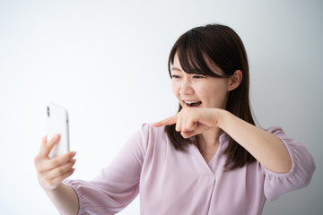 Fototapeta premium Angry business woman talking on smart phone against white wall
